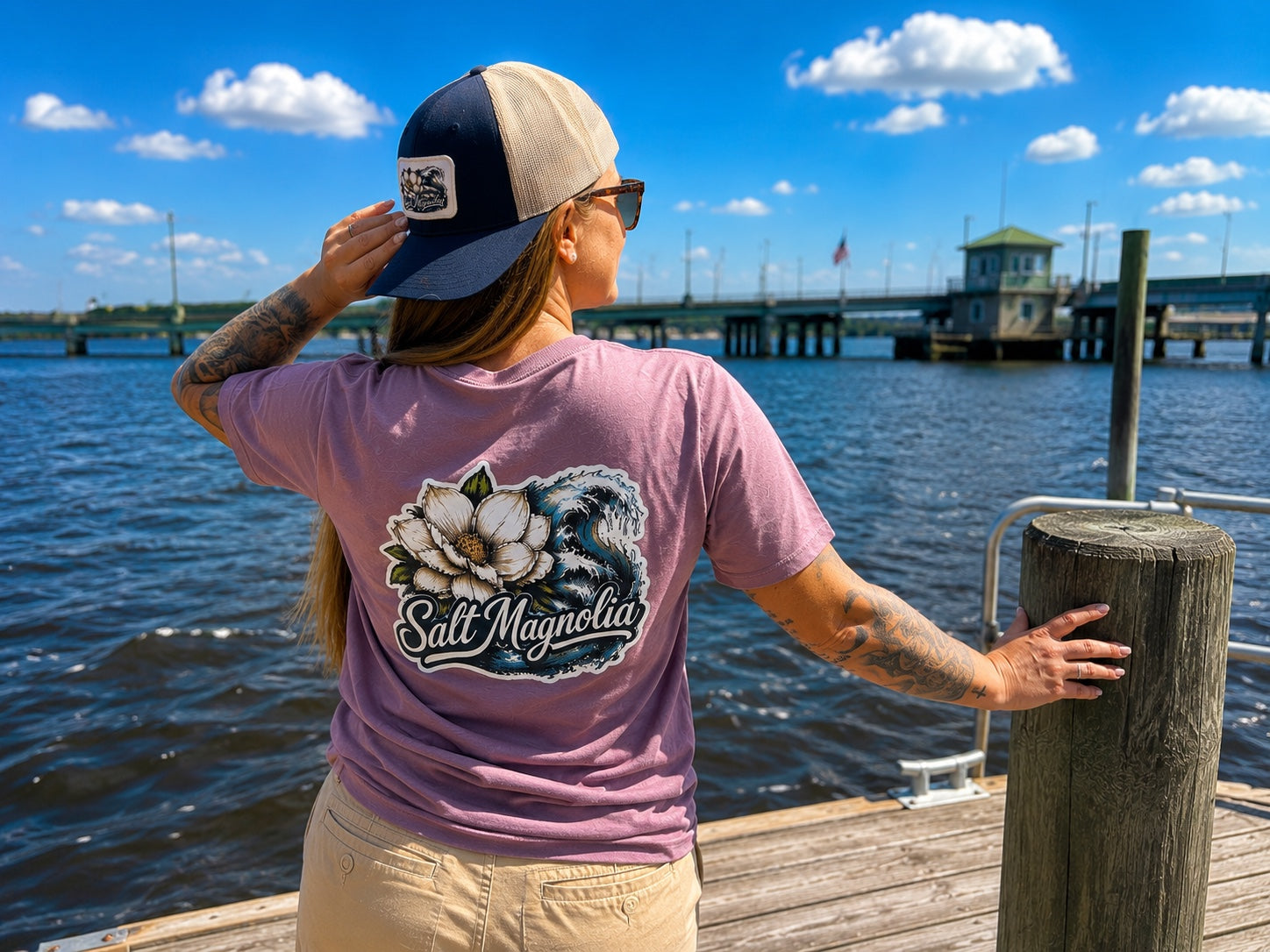 A Salt Magnolia shirt and hat on a dock by the water